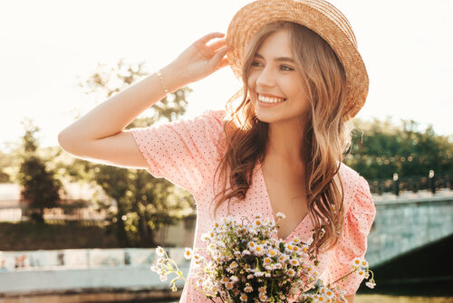 carefree woman posing on the street background in hat at sunset.