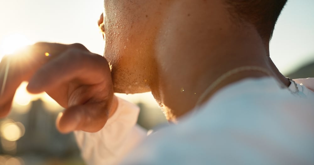 Close-up of athlete wiping sweat from chin outdoors, concept of fitness, cardio exercise, and marathon workout intensity.