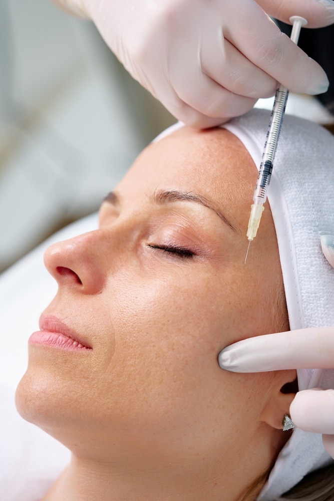 Close-up of young woman receiving Dysport injection at beauty clinic for wrinkle reduction and facial rejuvenation.